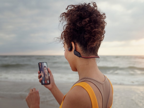 Ženska uživa v kristalno jasnem telefonskem klicu s kostnoprevodnimi slušalkami Philips