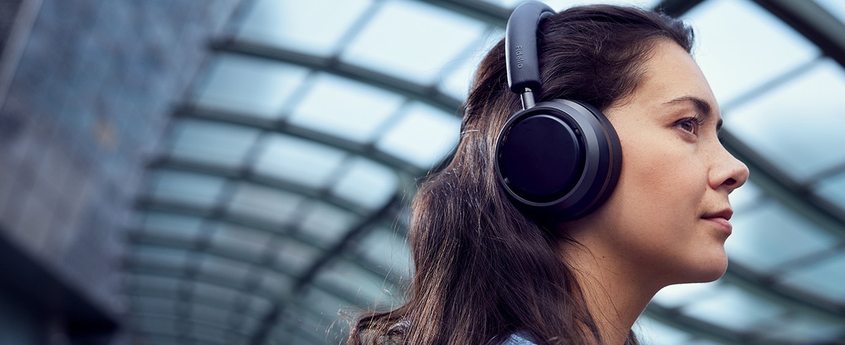 Ženska, ki na potovanju uživa v glasbi s slušalkami Philips L4
