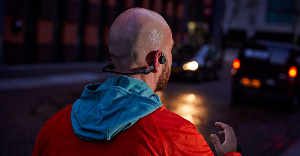 moški, ki nosi slušalke z odprtimi ušesi na natrpani ulici