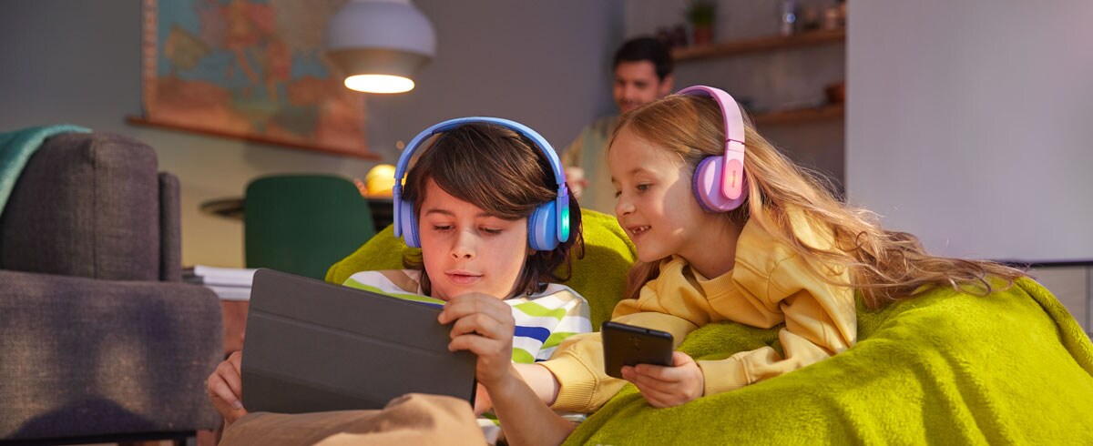 Deček in deklica skupaj s trpežnimi otroškimi slušalkami uporabljata tudi druge naprave