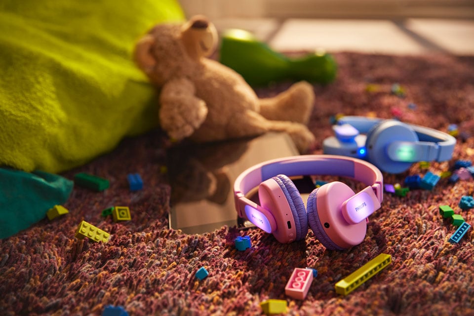 Modre in roza otroške slušalke na tleh z igračami