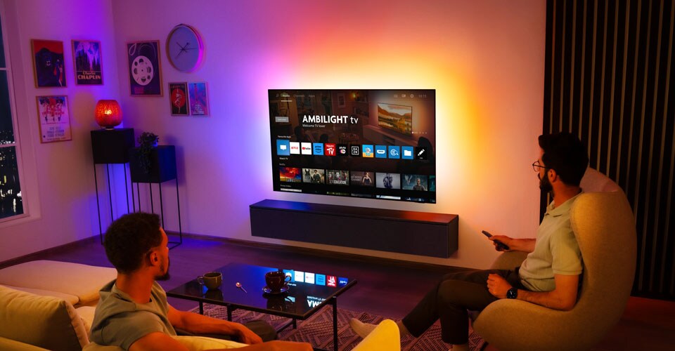 Dva moška gledata na stensko nameščen televizor Ambilight v dnevni sobi