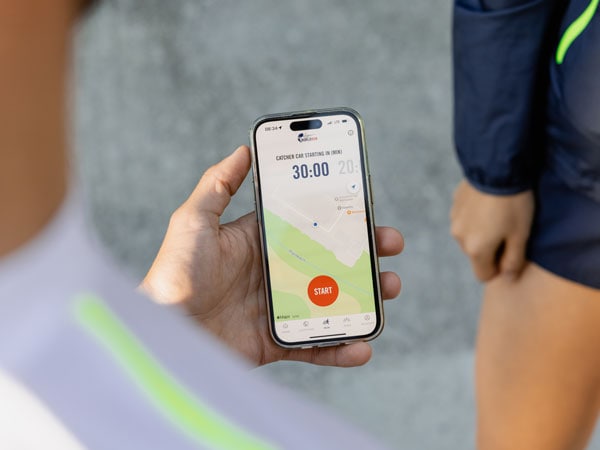 Udeleženec teka preverja na telefonu, kdaj bo dan znak za začetek teka.