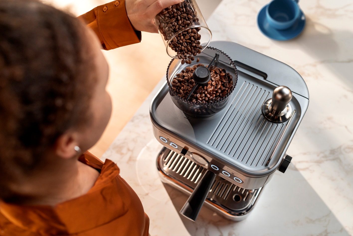 Mlada ženska v posodo za kavna zrna Barista Brew dodaja kavna zrna